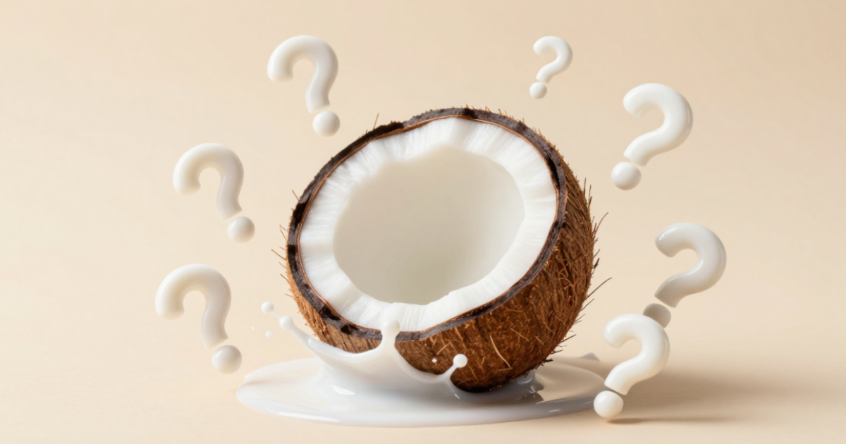 Mitad de coco sobre fondo beige rodeada de signos de interrogación blancos y salpicaduras de leche, representando los mitos y preguntas sobre la leche de coco.
